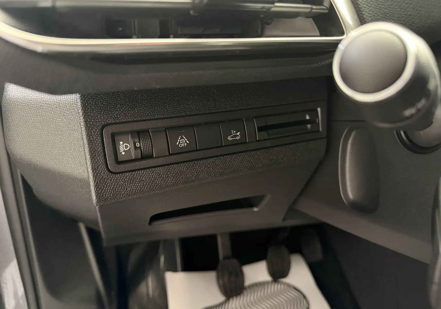 Vue rapprochée du tableau de bord côté gauche du Peugeot 3008 gris Artense, montrant les commandes d'assistance et réglage des phares.