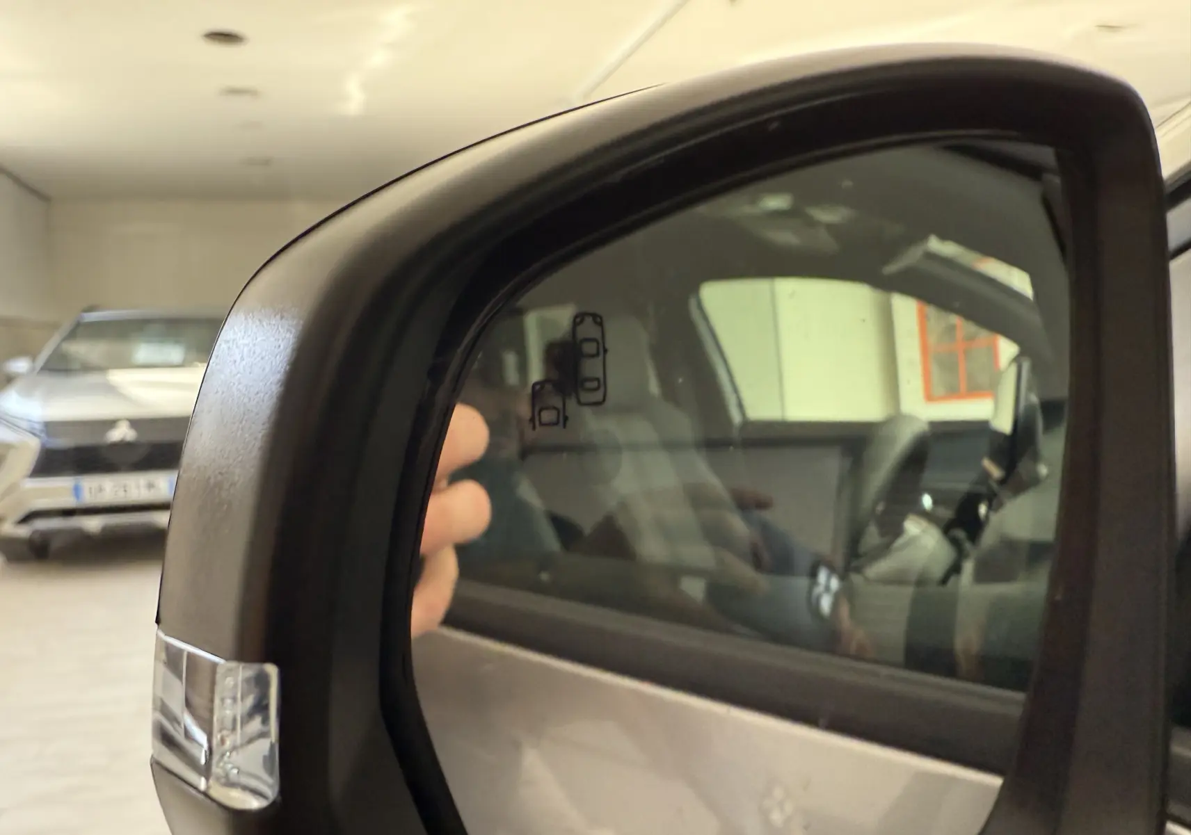 Rétroviseur côté droit du Peugeot 3008 gris Artense Metal 2023, avec reflet de l'intérieur et pictogrammes de sécurité.