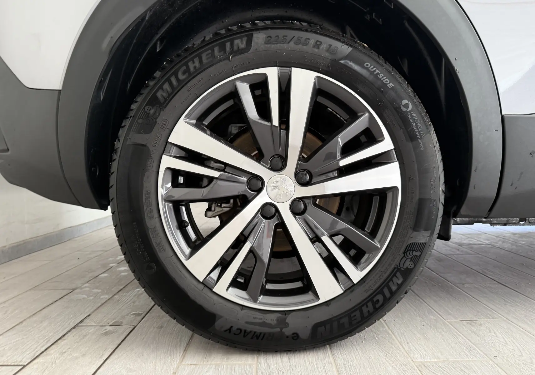 Gros plan sur la roue avant droite d'un Peugeot 3008 gris Artense avec jante alliage et pneu Michelin visible.