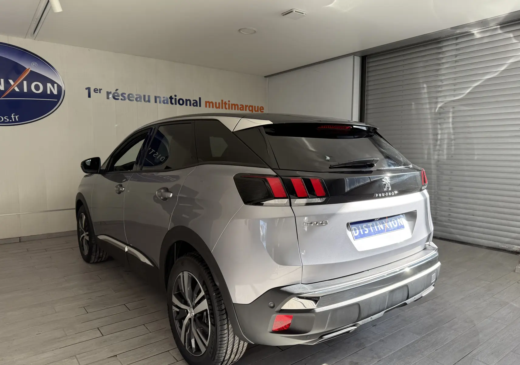 Vue 3/4 arrière droite d'un Peugeot 3008 gris Artense métal avec toit noir et feux arrière à griffes rouges.
