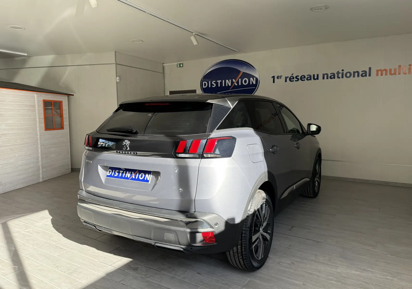 Vue 3/4 arrière droite d'un Peugeot 3008 gris Artense métal avec vitres teintées et feux arrière à griffes rouges.