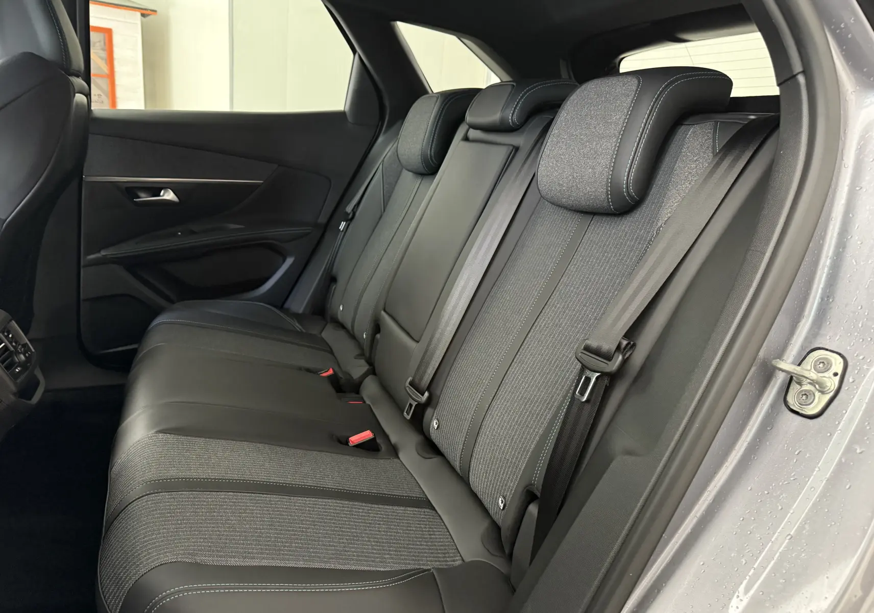 Vue intérieure côté droit des sièges arrière en tissu et cuir du Peugeot 3008 gris Artense 2023.