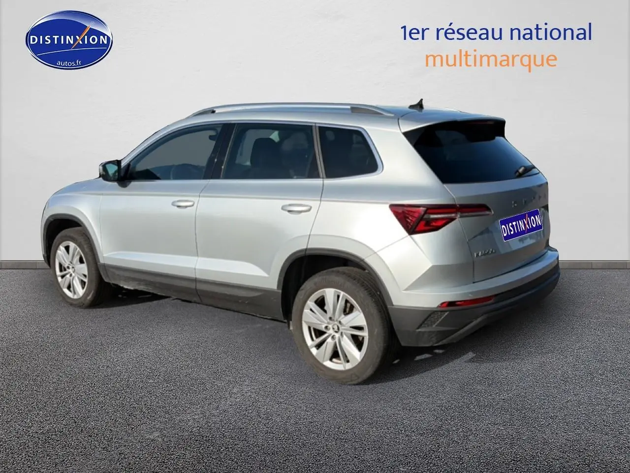 Vue 3/4 arrière droite d'un Skoda Karoq gris avec barres de toit et jantes alliage.