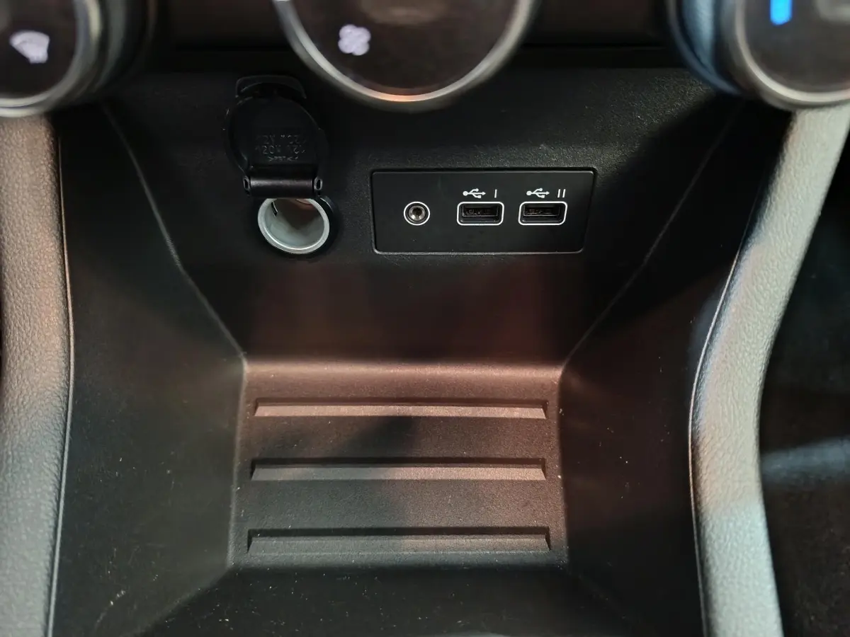 Gros plan sur la console centrale noire de la Renault Clio Evolution Blue dCi 100, avec prises USB et prise 12V visibles.