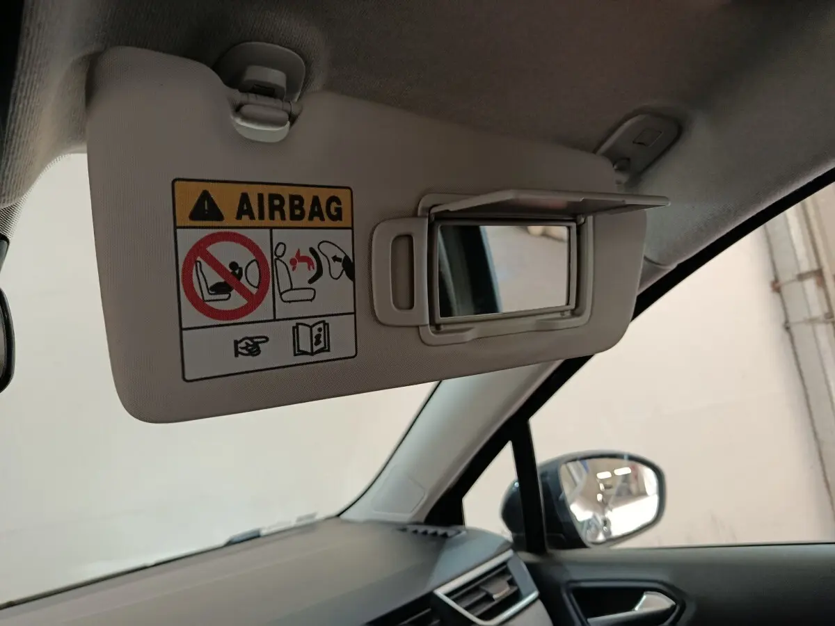 Vue intérieure côté conducteur sur le pare-soleil beige avec miroir et avertissement airbag de la Renault Clio noire.