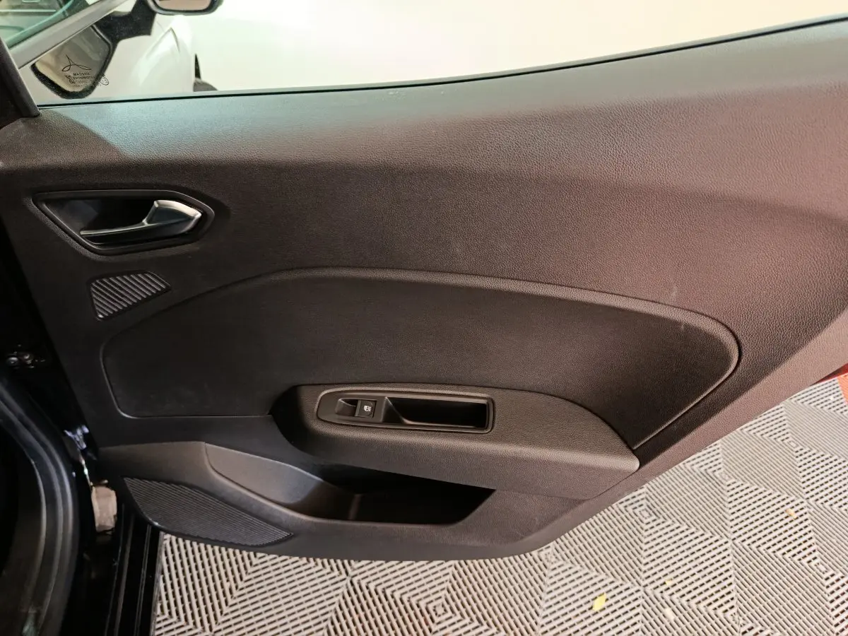 Vue rapprochée de la porte intérieure côté gauche noire de la Renault Clio Evolution Blue dCi 100, avec poignée et commande de fenêtre.