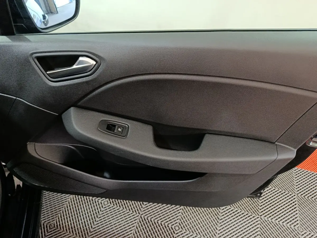 Vue intérieure du panneau de porte côté gauche de la Renault Clio noire, avec commande de lève-vitre électrique intégrée.