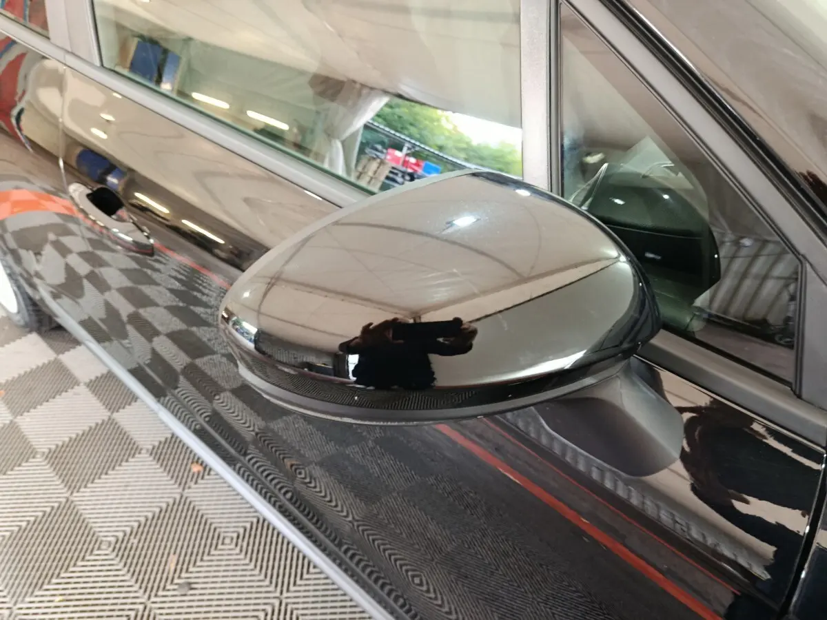 Rétroviseur extérieur droit noir brillant de Renault Clio Evolution Blue dCi 100, vue rapprochée sur la portière noire.