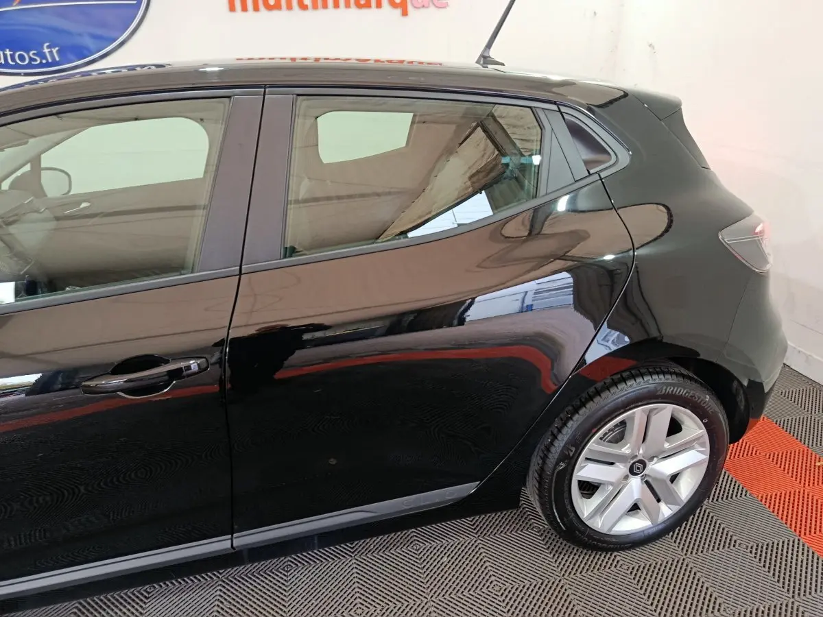 Vue latérale droite d’une Renault Clio noire 2025, mettant en valeur la porte arrière et la roue arrière avec jante argentée.