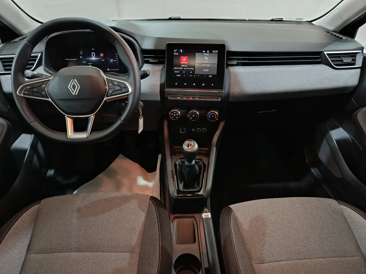 Vue intérieure avant de la Renault Clio Evolution Blue dCi 100 2025, tableau de bord gris avec écran tactile central et volant multifonctions.