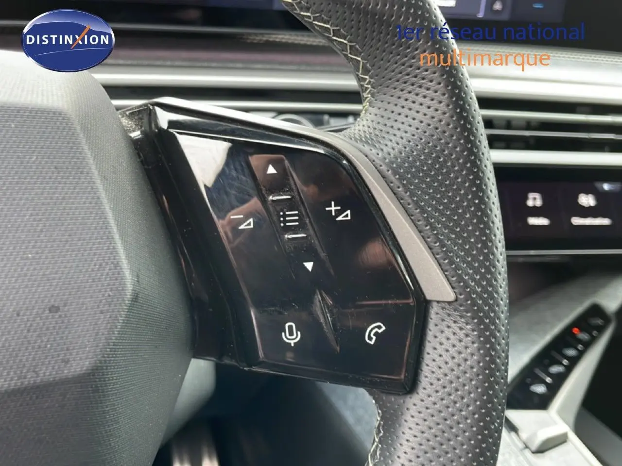 Gros plan sur les commandes gauche du volant perforé gris noir du Peugeot 3008 2025, avec touches audio et téléphone.