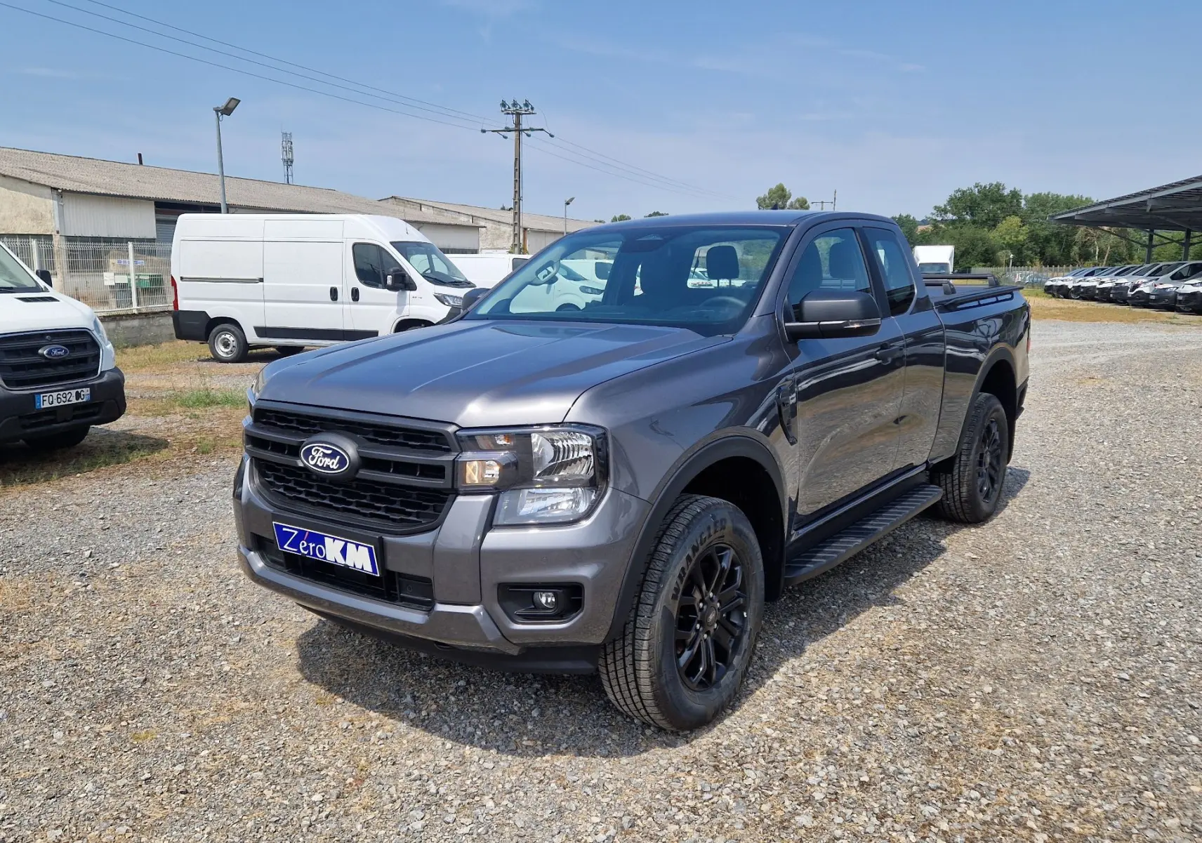 Ford Ranger Super Cabine gris carbone vu en 3/4 avant droit, avec marchepieds et jantes noires.