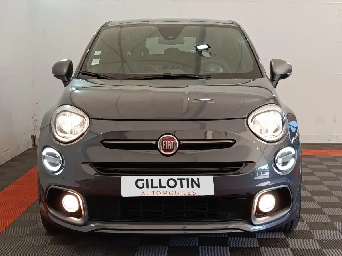 Vue frontale d'une Fiat 500X gris foncé avec feux LED allumés et logo Fiat bien visible sur calandre.