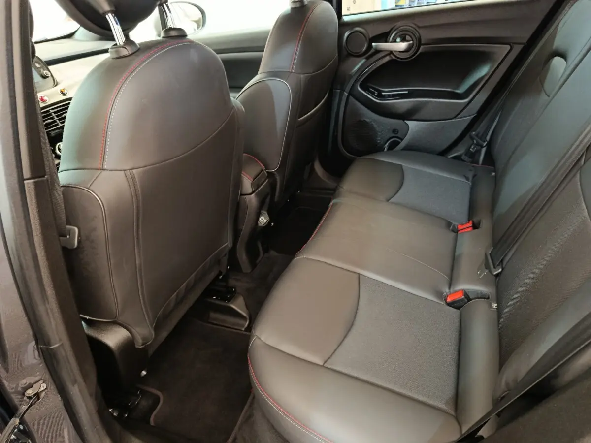 Vue intérieure arrière côté gauche de la Fiat 500X 2021, sièges en cuir noir avec surpiqûres rouges.