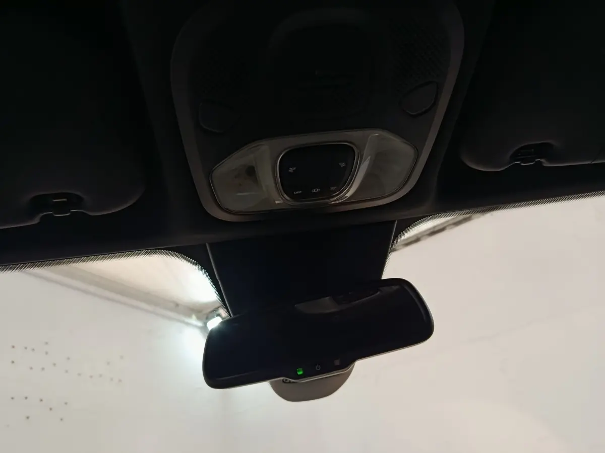 Vue intérieure du rétroviseur central et plafonnier avec commandes lumineuses du Fiat 500X gris foncé 2021.