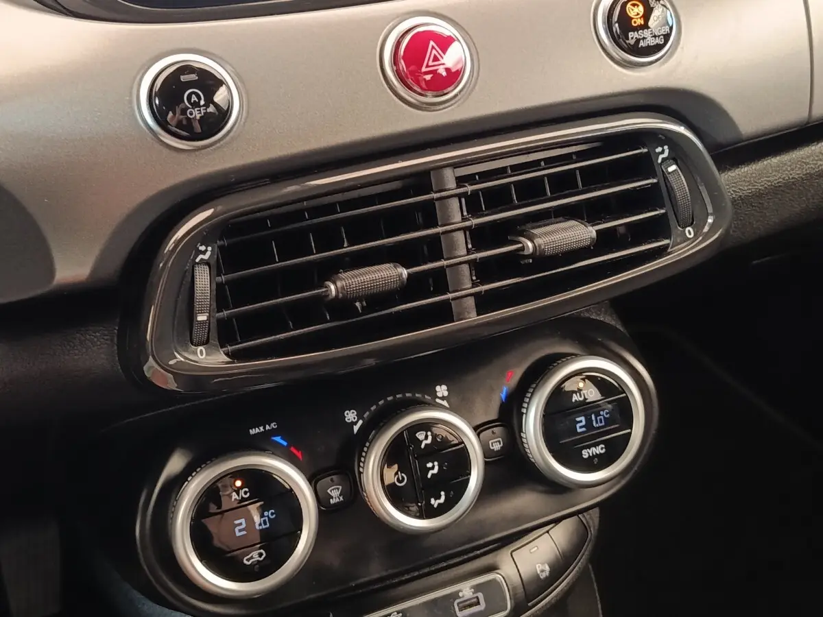 Détail du tableau de bord gris foncé de la Fiat 500X 2021 montrant les commandes de climatisation automatique bi-zone.