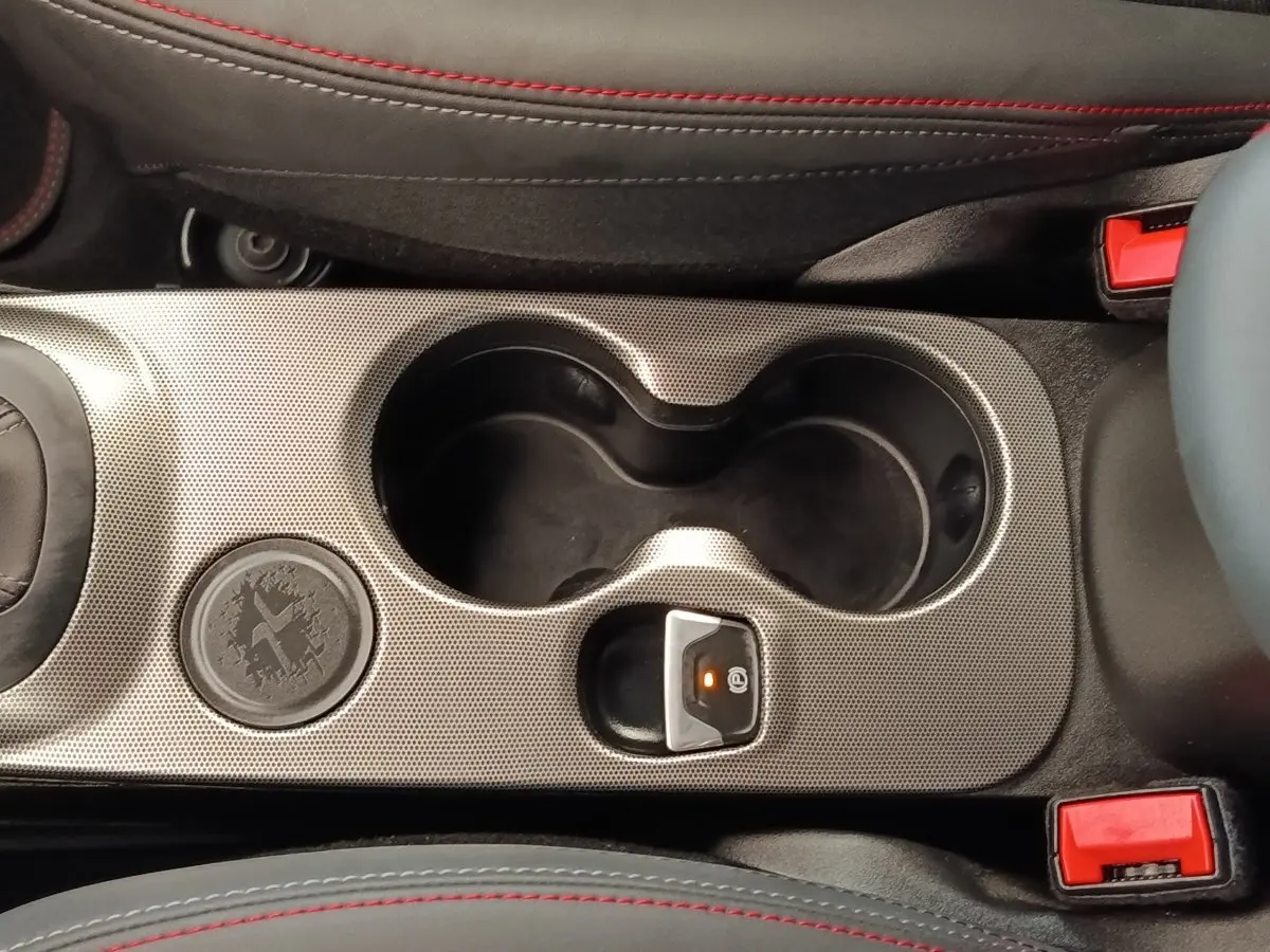 Gros plan sur la console centrale grise avec porte-gobelets et frein à main électrique de la Fiat 500X gris foncé.