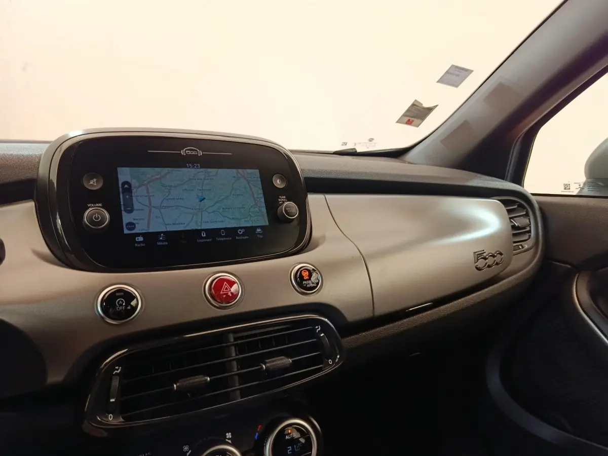 Vue intérieure du tableau de bord gris clair de la Fiat 500X 2021 avec écran tactile de navigation et commandes centrales.