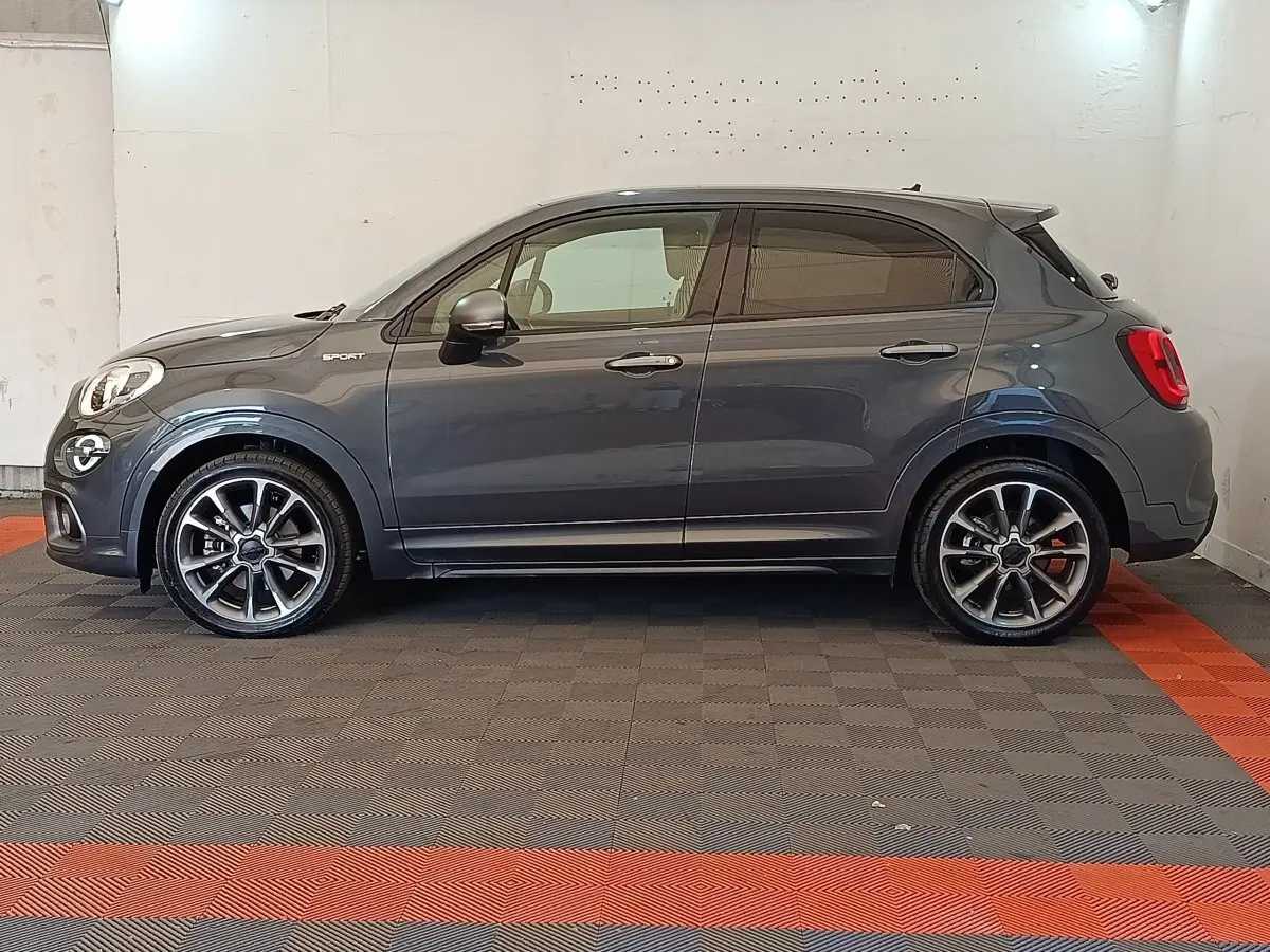 Profil droit d'un FIAT 500X gris foncé 2021 version Sport avec jantes alliage et logo "Sport" sur aile avant.