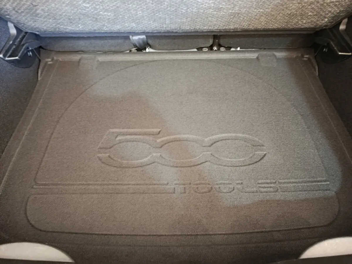 Vue plongeante sur le coffre avec tapis gris foncé embossé du logo 500X, banquette arrière rabattue visible en arrière-plan.