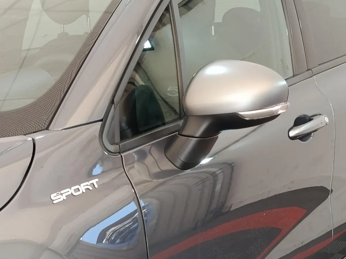 Gros plan sur le rétroviseur droit gris argenté et l’inscription Sport sur la porte gris foncé d’un Fiat 500X.