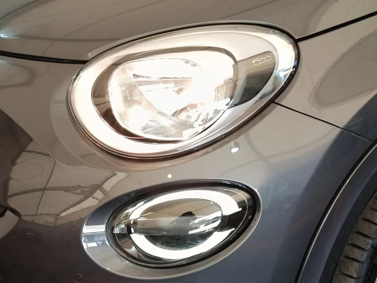 Gros plan sur les phares avant droit gris foncé d'une FIAT 500X 2021 avec éclairage LED et logo 500C visible.