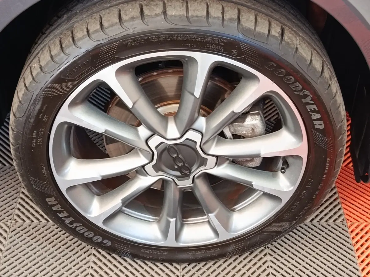 Gros plan sur la jante alliage gris argenté et pneu Goodyear d'une Fiat 500X gris foncé, vue côté roue arrière.