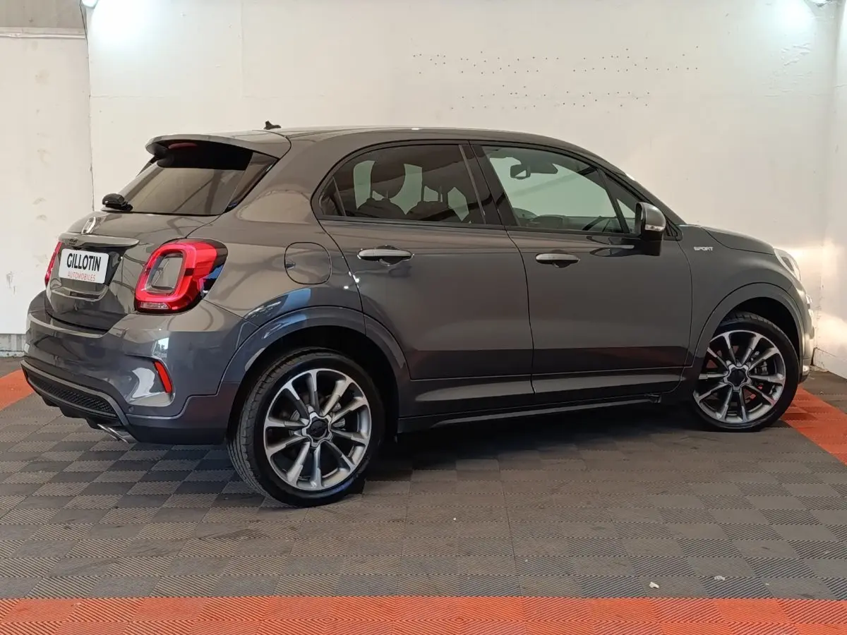 Vue latérale droite d'un FIAT 500X gris foncé avec jantes alliage et badge Sport sur l'aile avant.