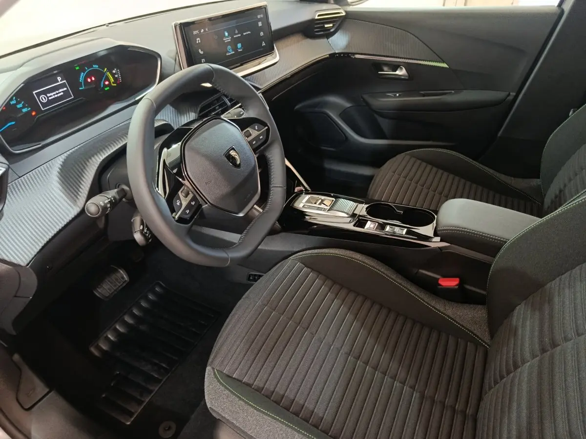 Intérieur avant droit de la Peugeot 208 électrique gris clair, volant cuir multifonctions et écran tactile central.
