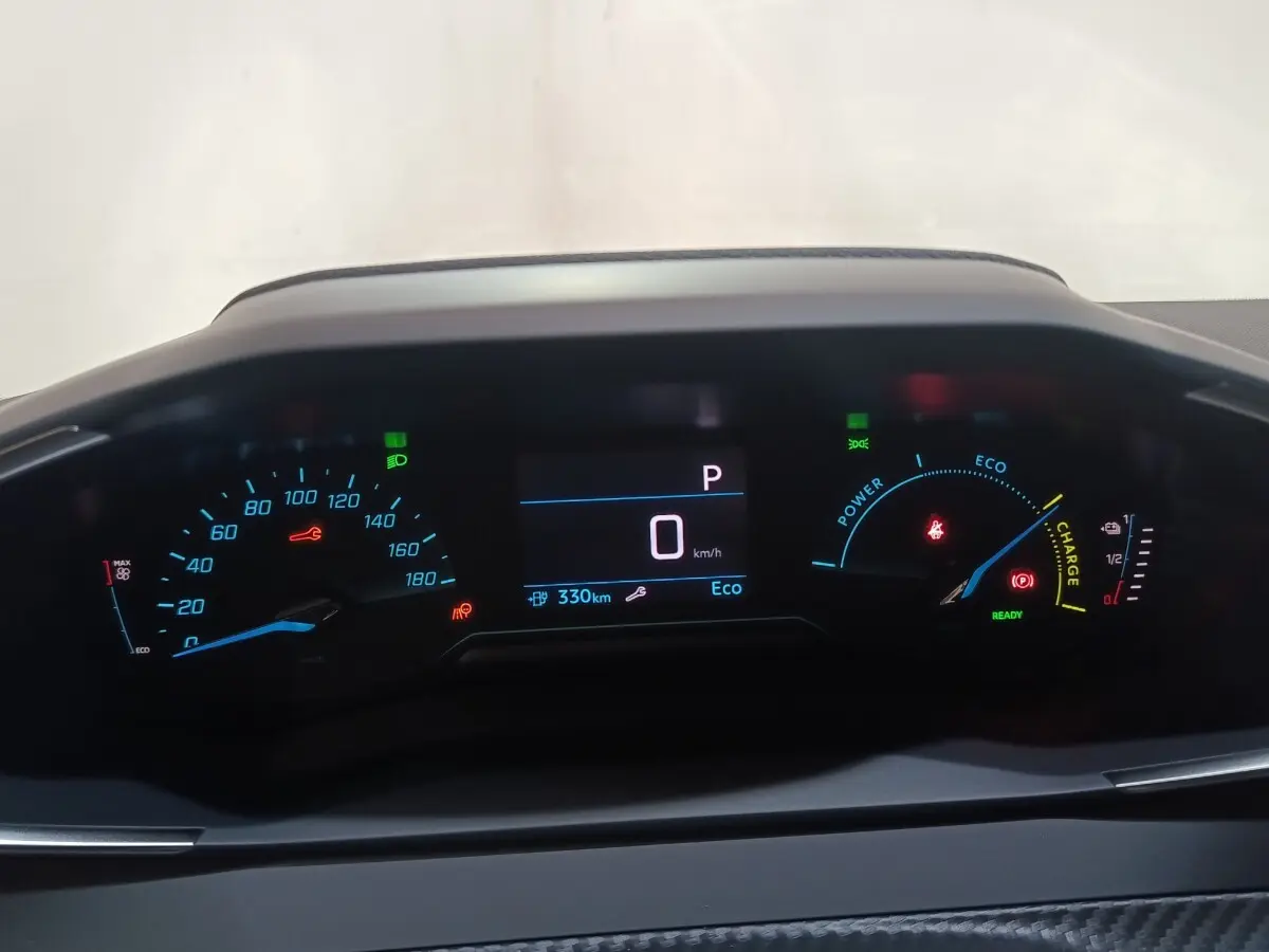 Tableau de bord numérique de Peugeot 208 électrique 2024 affichant vitesse, autonomie et indicateurs énergie en vue frontale.