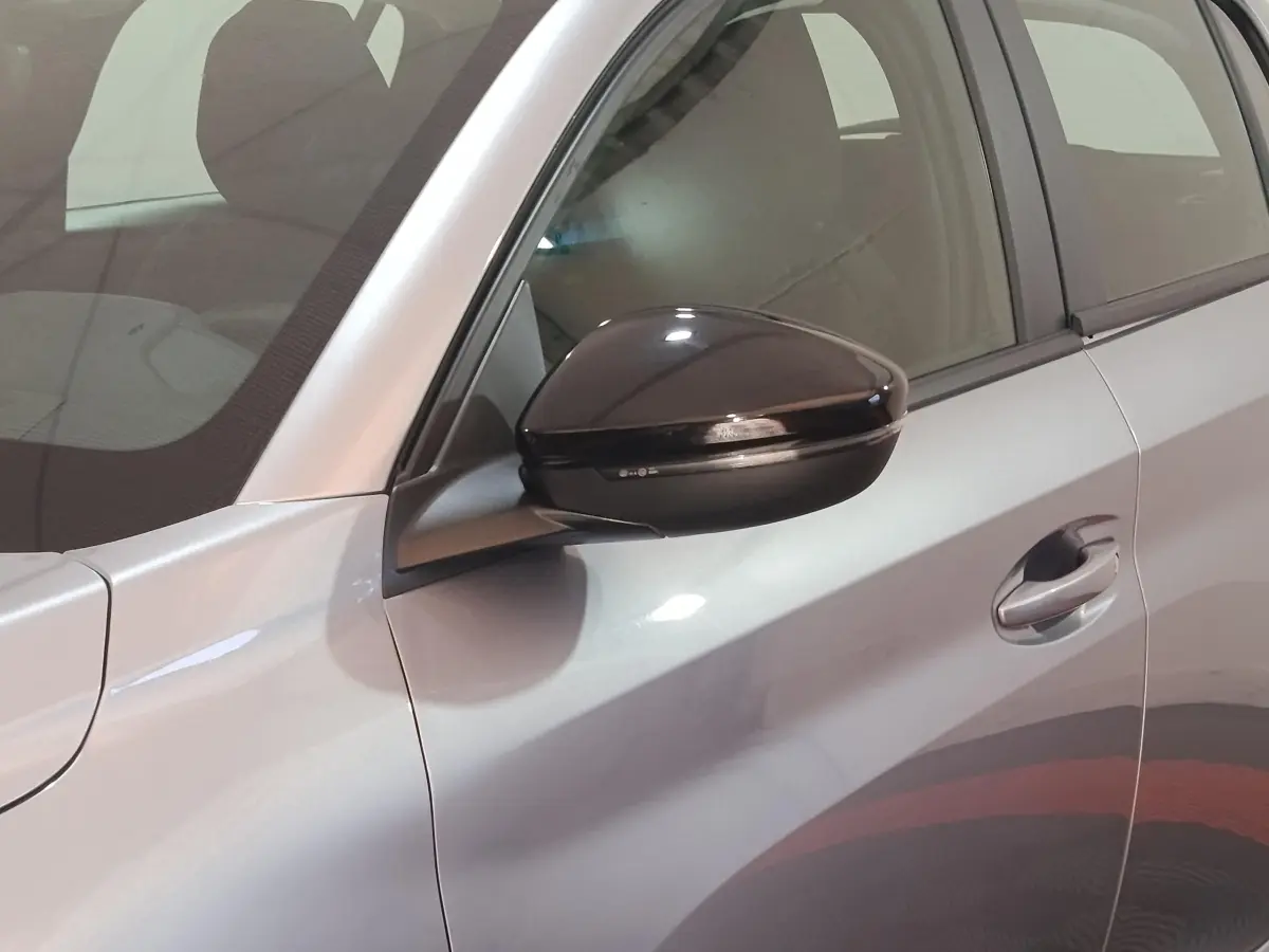 Gros plan sur le rétroviseur noir et la portière côté gauche d'une Peugeot 208 électrique gris clair.
