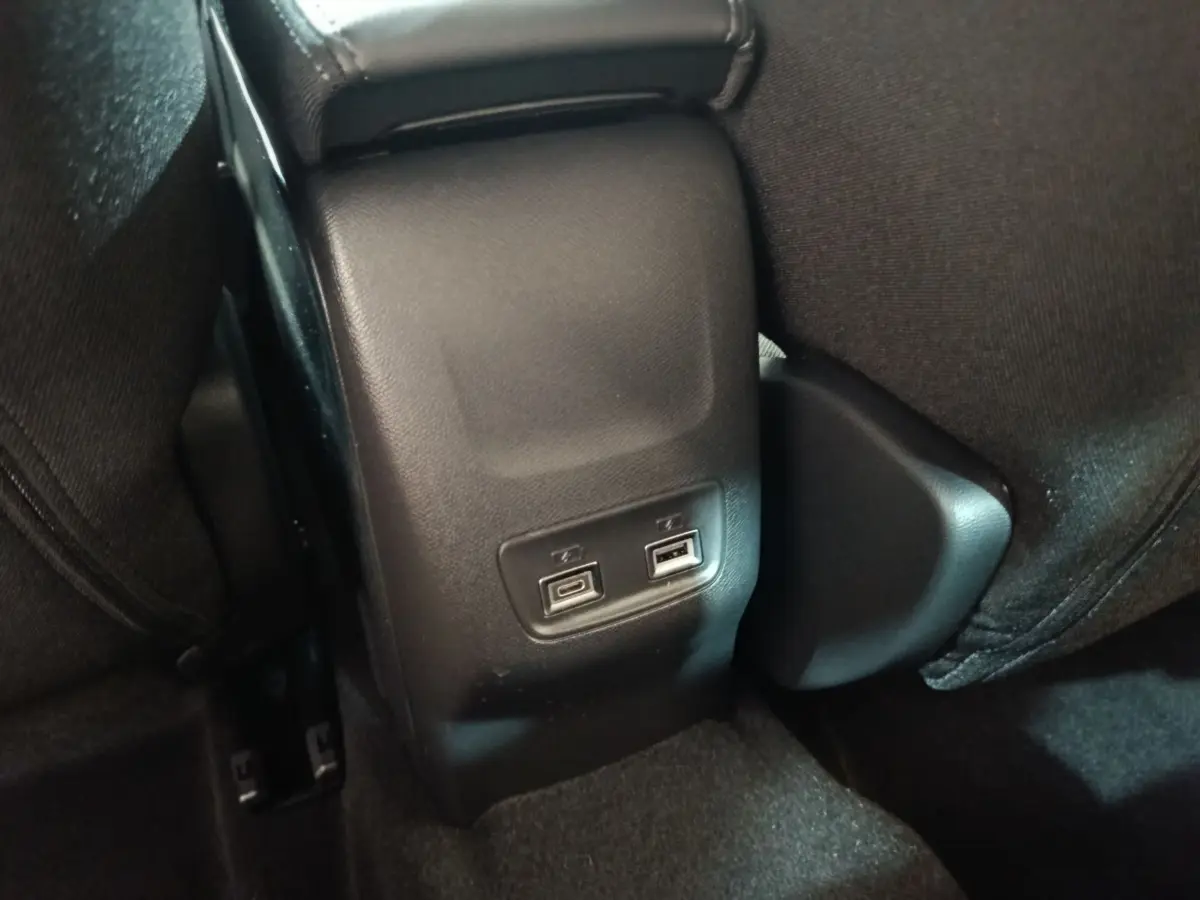 Prise USB double vue en gros plan à l'arrière de la console centrale d'une Peugeot 208 électrique gris clair.