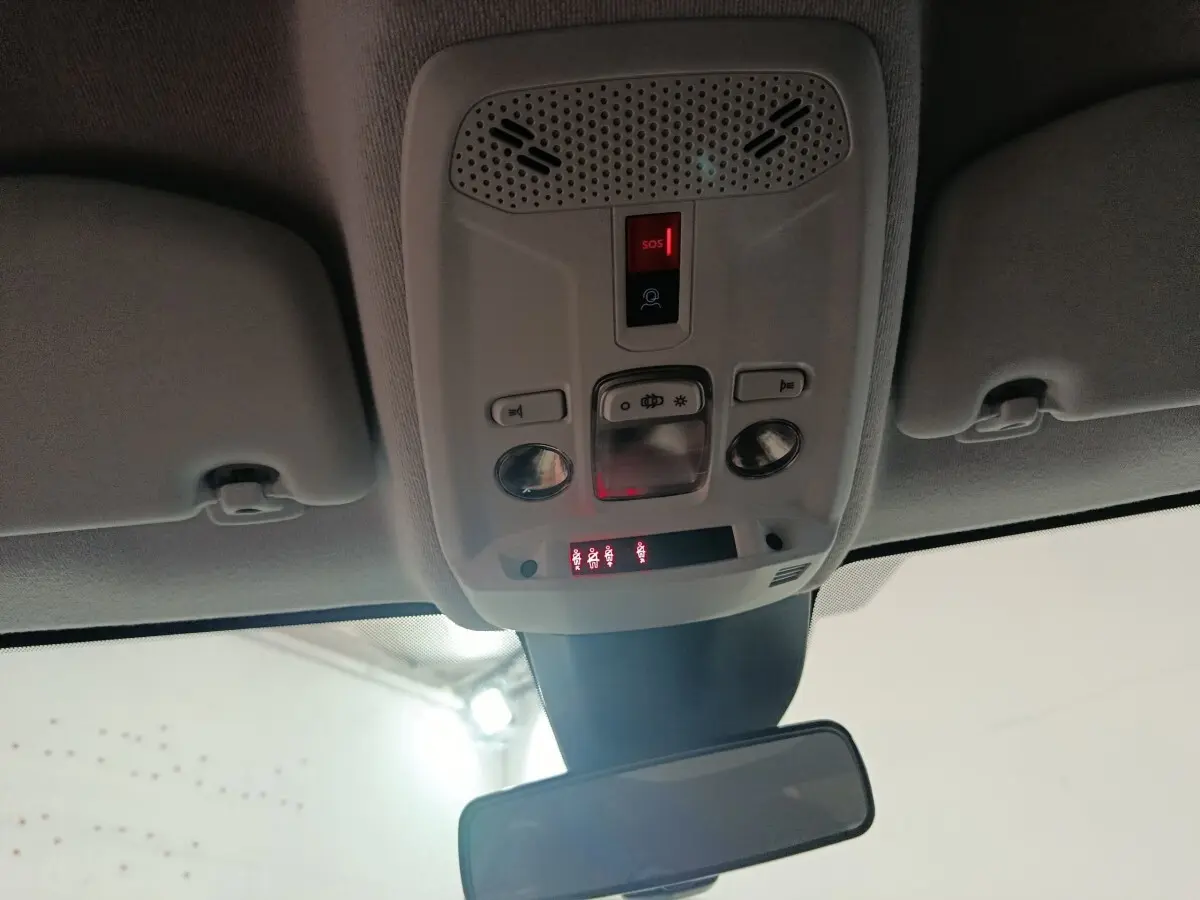 Vue intérieure du plafonnier gris clair avec commandes d’éclairage et bouton SOS allumé sur Peugeot 208 électrique 2024.