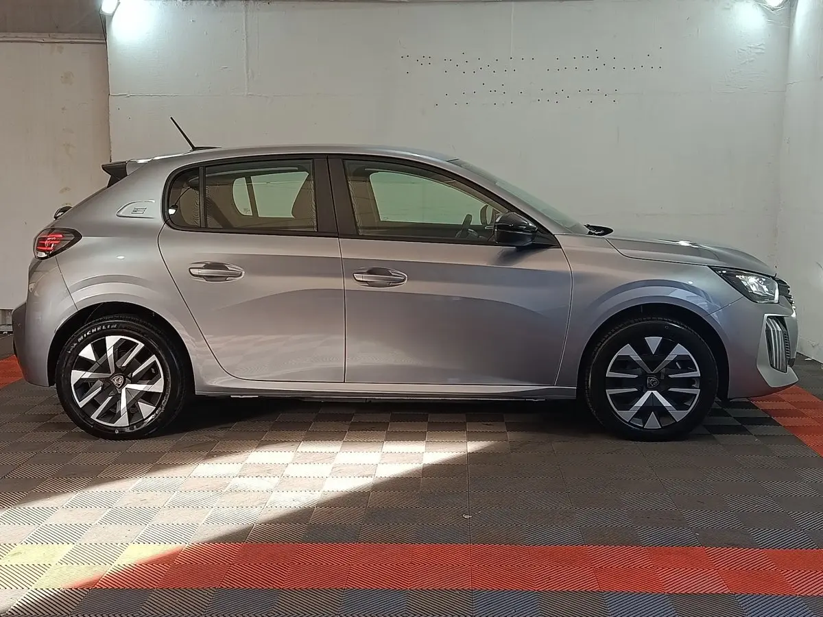 Peugeot 208 électrique gris clair vue de profil côté gauche, avec jantes au design moderne et feux arrière LED.