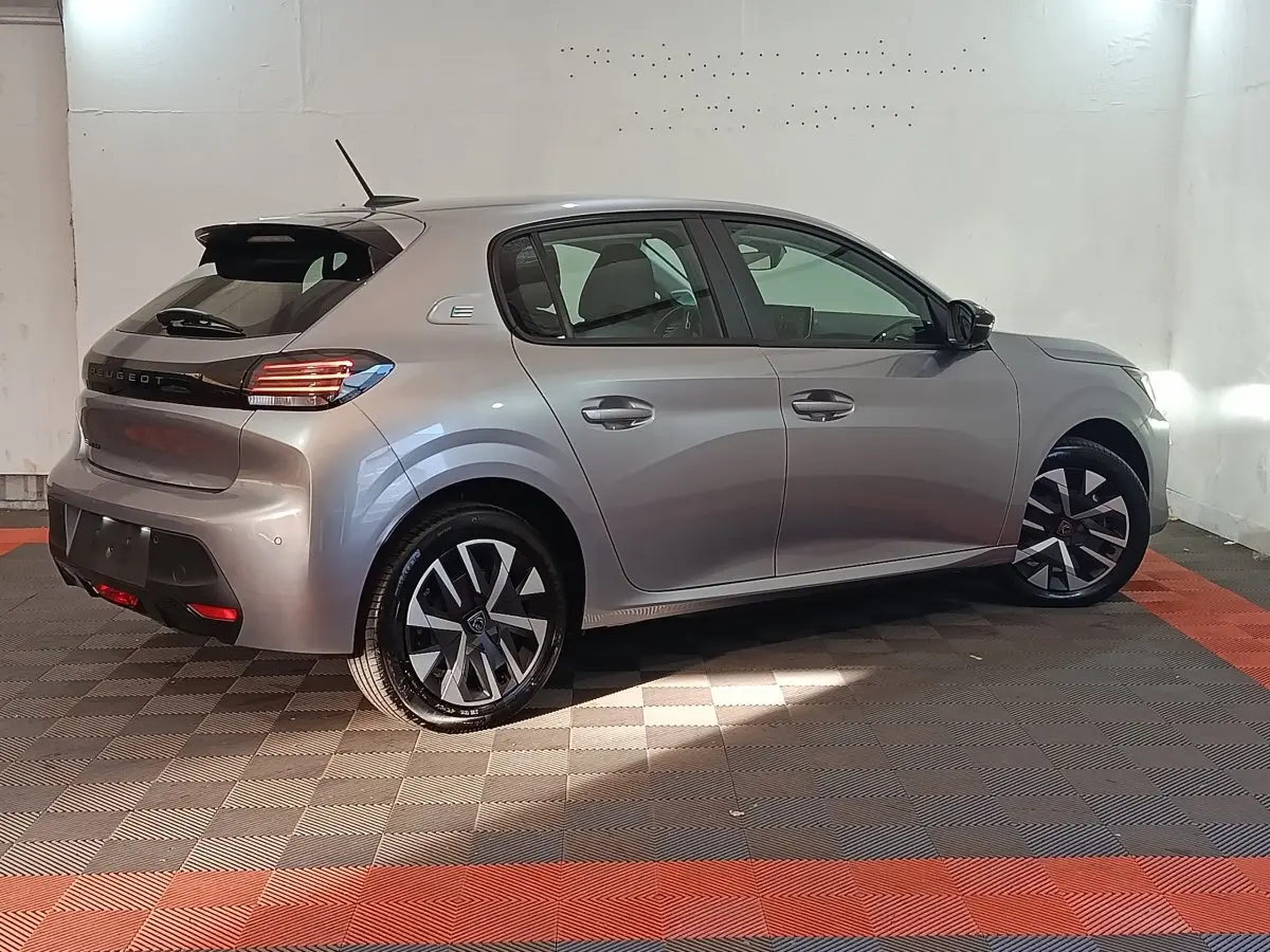 Peugeot 208 électrique gris clair vue de profil côté droit, avec jantes modernes et feux arrière LED distinctifs.