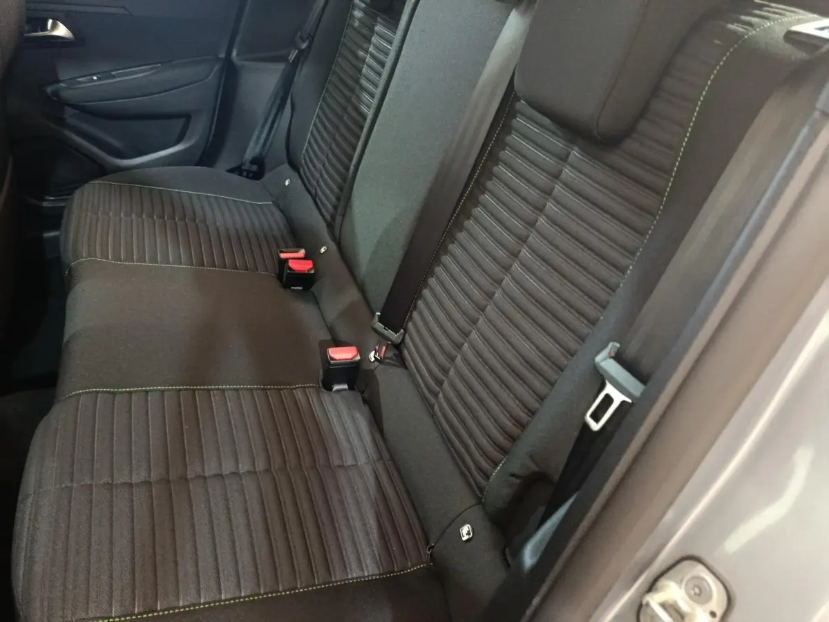 Vue côté droit sur la banquette arrière noire avec coutures vertes d’une Peugeot 208 électrique gris clair 2024.