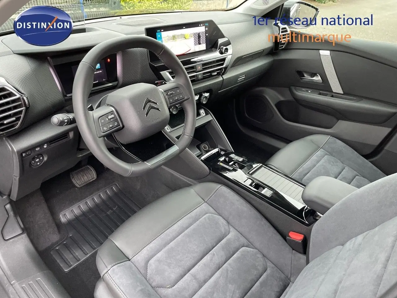 Intérieur moderne de la Citroën C4 2024, vue côté conducteur, sièges gris cuir et alcantara, tableau de bord avec écran tactile.