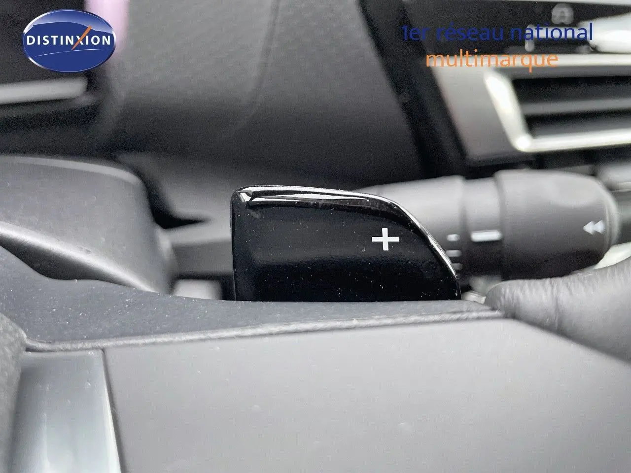 Gros plan sur la palette de changement de vitesse "+" côté droit du volant dans l'habitacle d'une Citroën C4 gris platinium 2024.