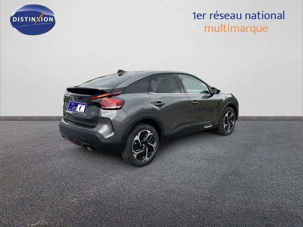 Citroën C4 gris platinium métal vue 3/4 arrière droit, avec jantes bicolores et toit noir contrasté.