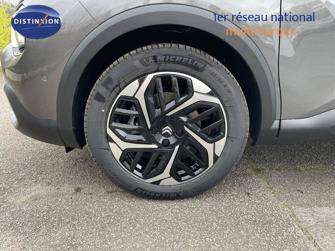 Gros plan sur la roue avant gauche d'une Citroën C4 gris platinium métal avec jante alliage noire et argent.