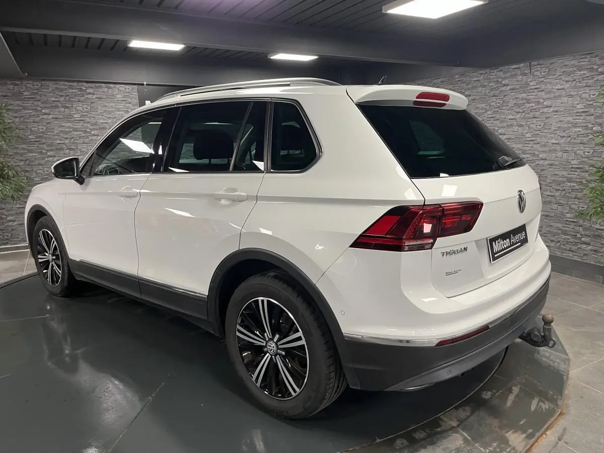 Volkswagen Tiguan blanc vu en 3/4 arrière droit, avec jantes alliage noires et crochet d'attelage escamotable.