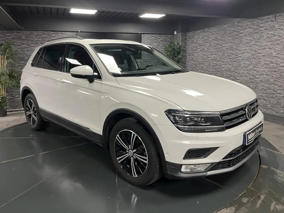 Volkswagen Tiguan blanc en 3/4 avant droit, avec jantes alliage noires et phares LED dans un showroom.