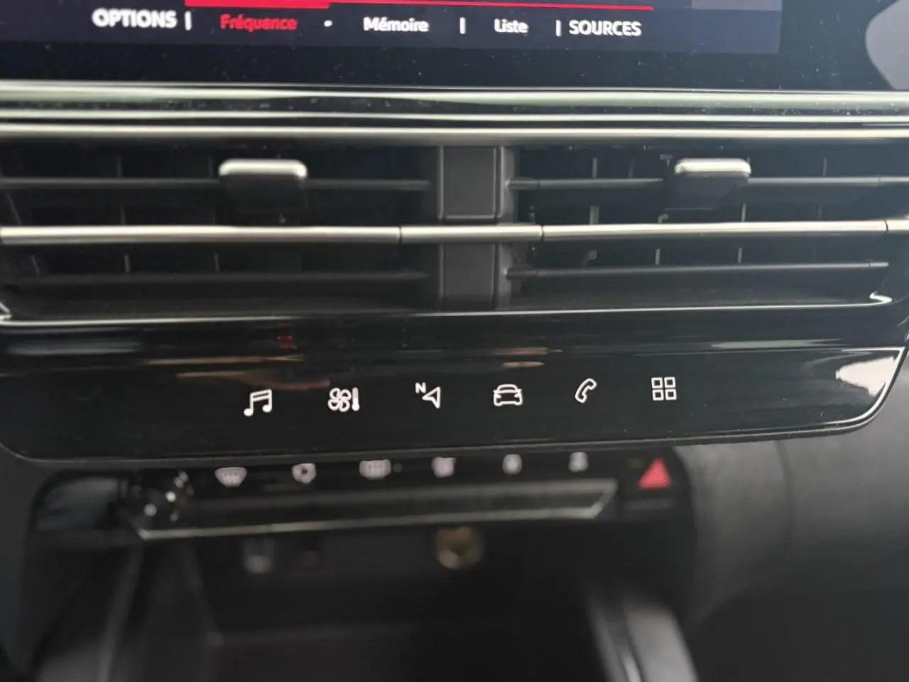 Détail du tableau de bord noir brillant avec commandes tactiles multimédia et climatisation du Citroën C5 Aircross Hybrid 2024.