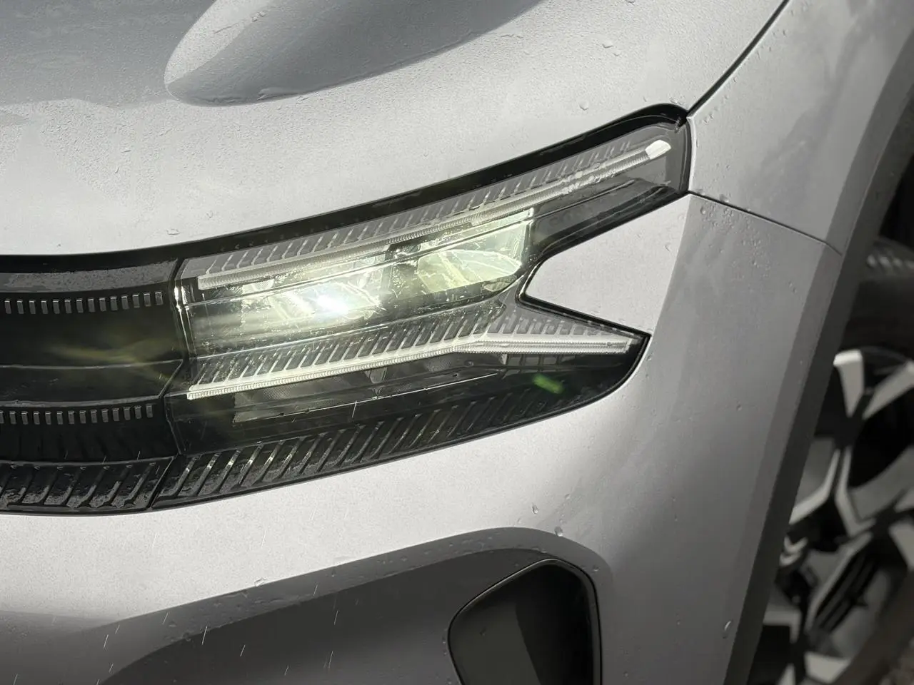 Gros plan sur le phare avant droit LED du Citroën C5 Aircross Hybrid gris Artense avec jante alliage visible.