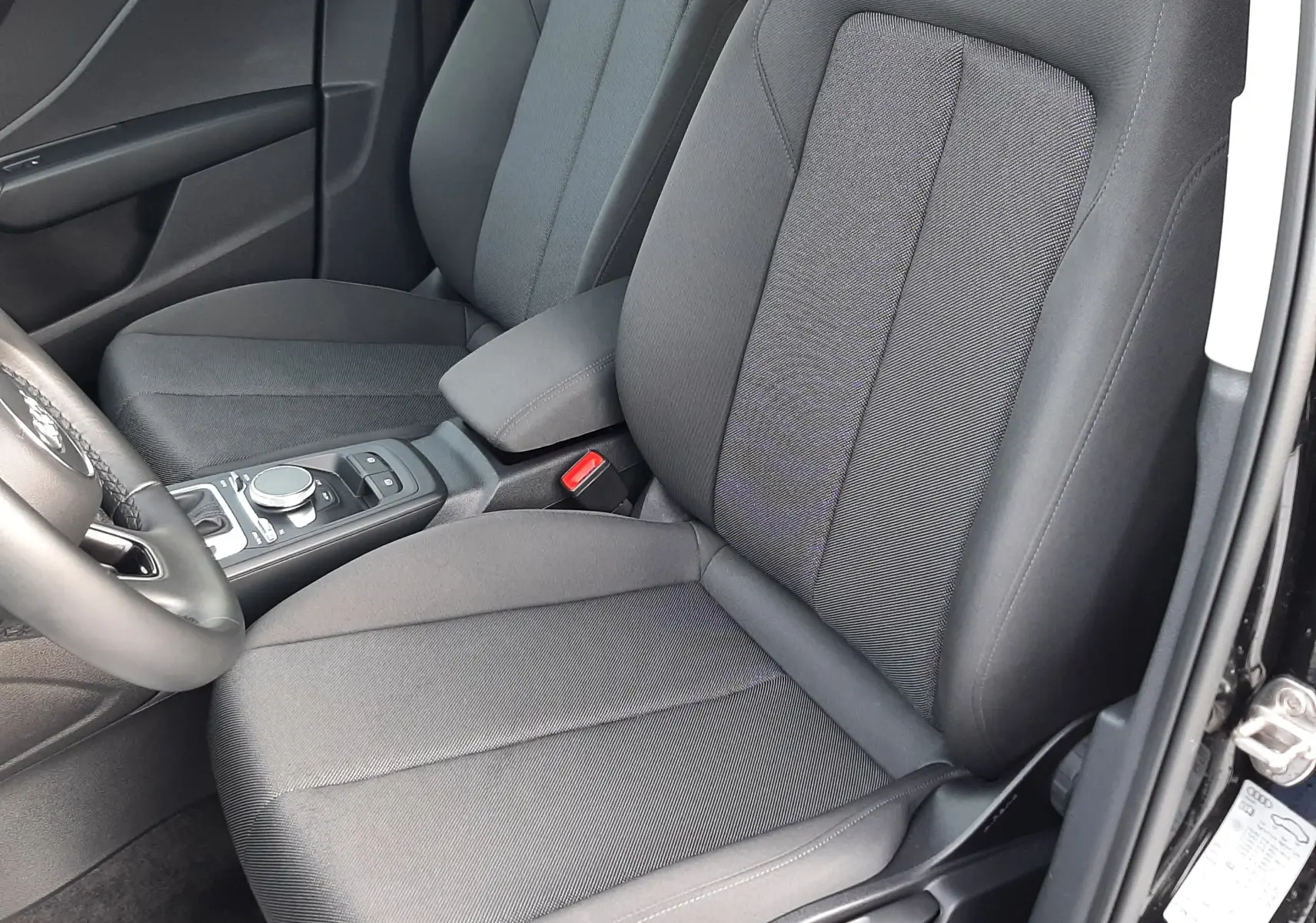 Intérieur avant droit de l'Audi Q2 35 TFSI S-Line 2023 avec sièges tissu gris foncé et console centrale noire.