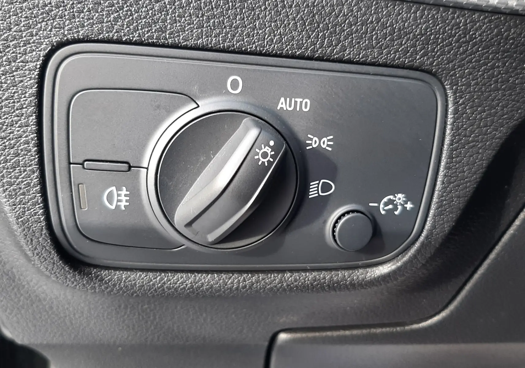 Gros plan sur le commutateur d'éclairage intérieur noir du tableau de bord de l'Audi Q2 35 TFSI S-Line 2023.