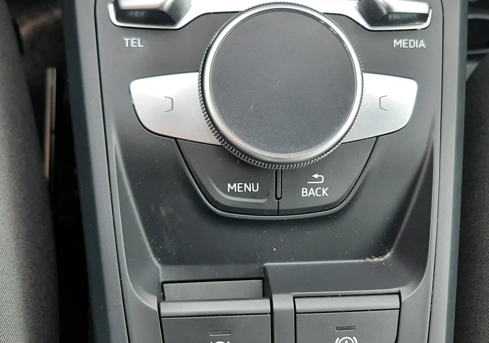 Gros plan sur la molette de commande centrale et les boutons de frein à main et auto-hold de l'Audi Q2 noir mito metal 2023.