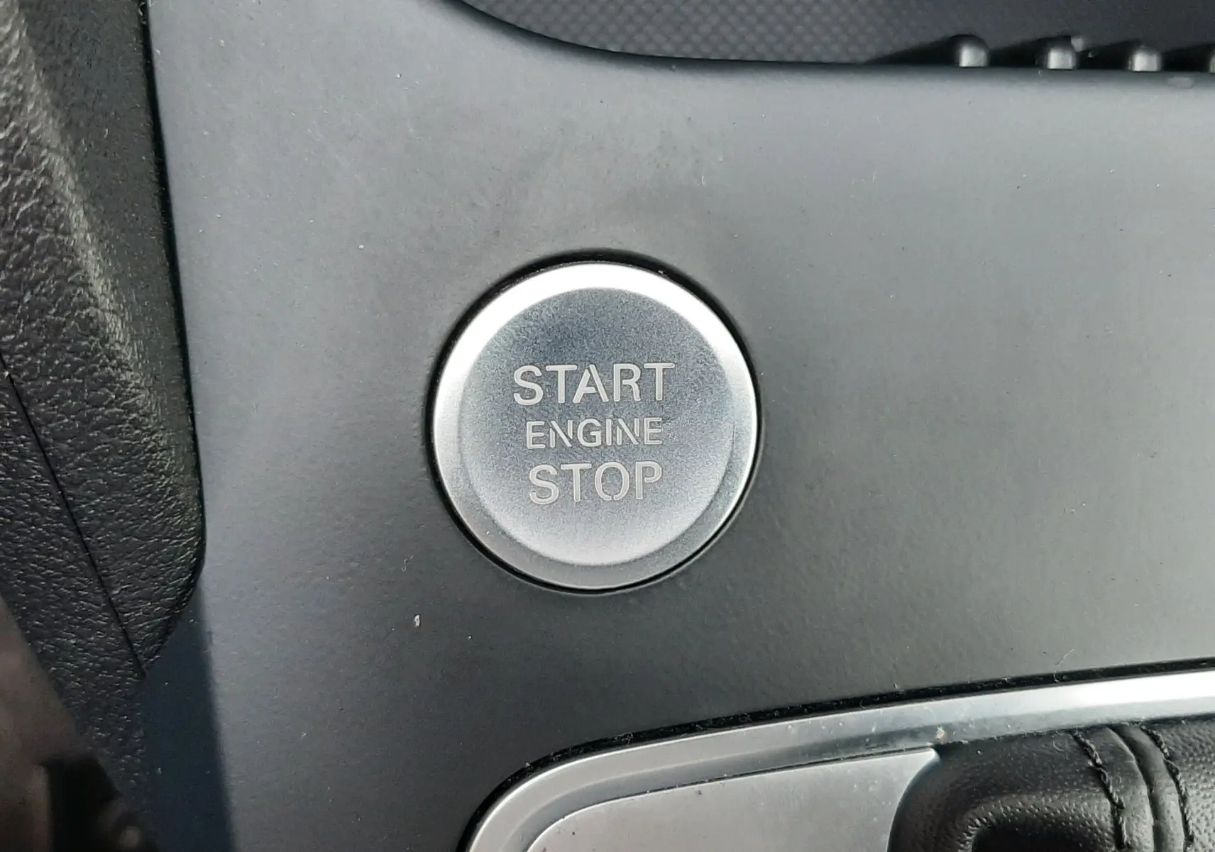 Bouton rond Start Engine Stop en métal brossé sur console noire de l'Audi Q2 35 TFSI S-Line 2023.