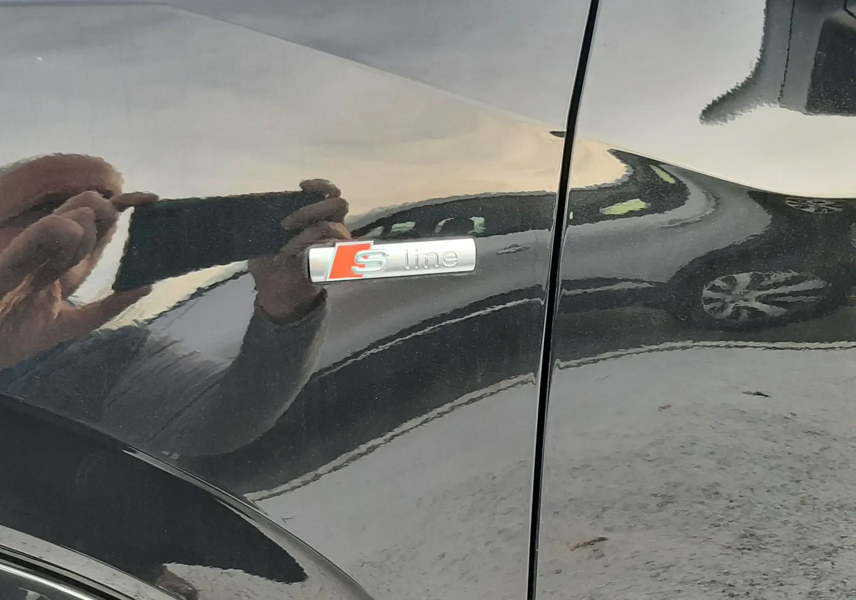 Gros plan sur l'emblème S line sur la portière noire métallisée d'un Audi Q2 2023.