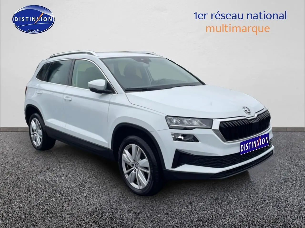 Vue 3/4 avant d'un Skoda Karoq blanc glacial avec calandre noire et jantes alu visibles.